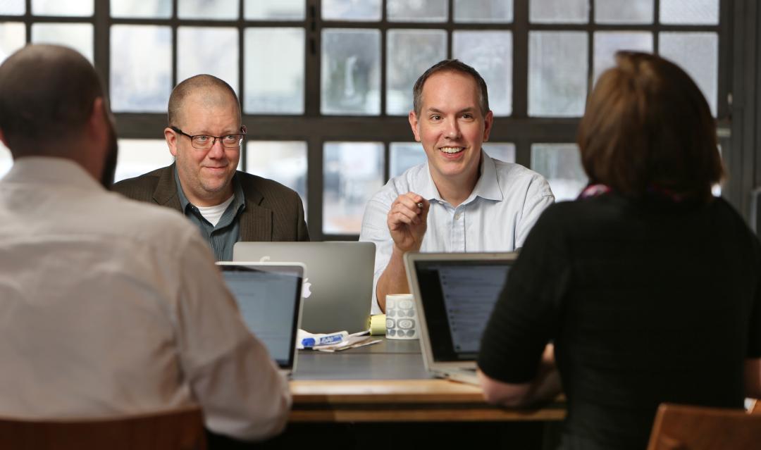 several team members at an office table, discussing strategy on a project