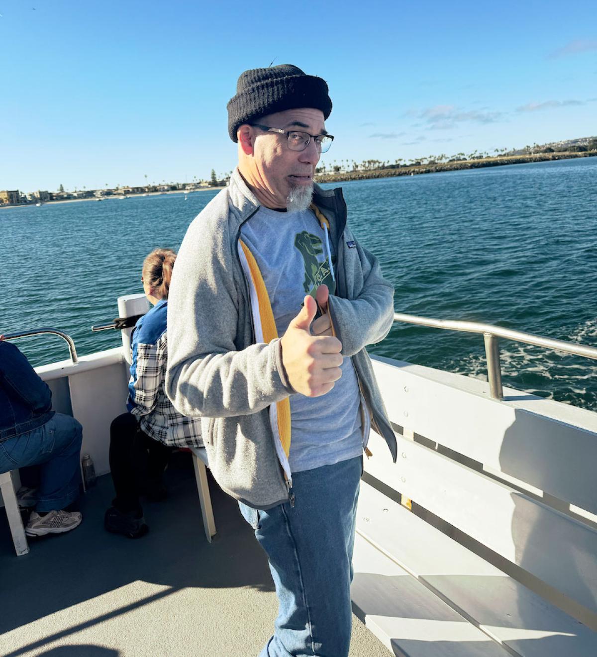 David on the boat giving a "thumbs up" with ocean in background