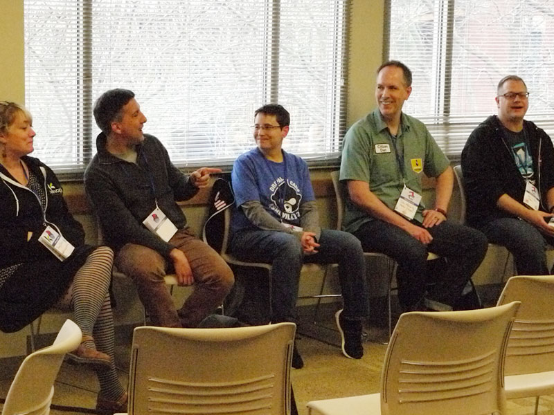 five speakers at conference talk, all sitting and interacting