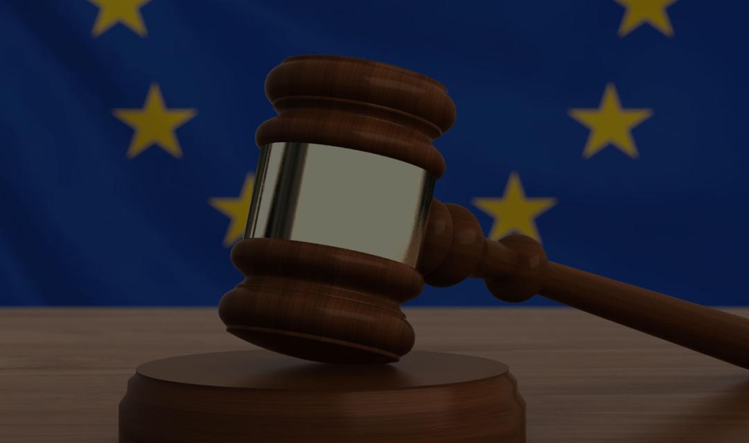 wooden gavel on a desk with the EU flag in the background
