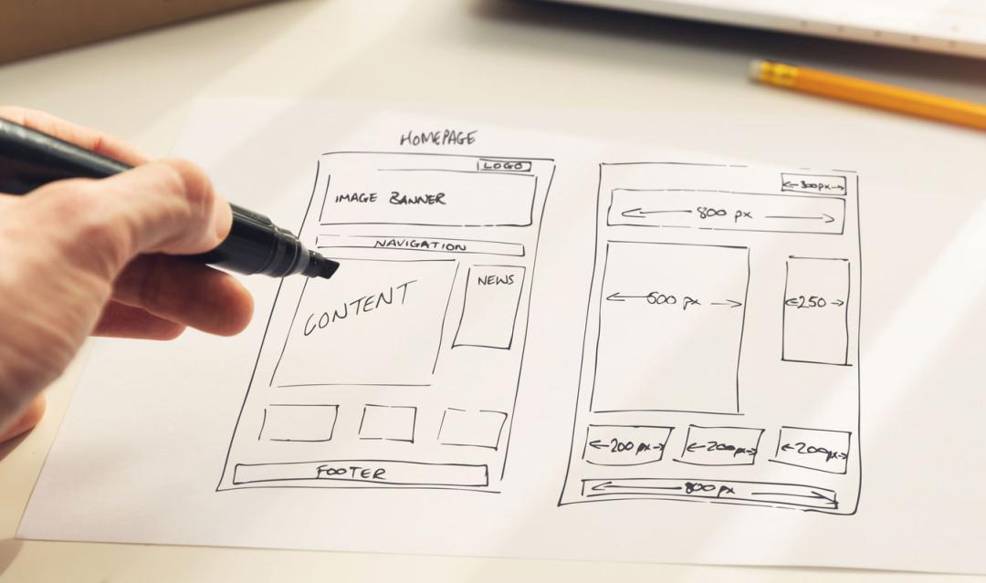 hand holding marker, sketching out a rough wireframe of page layout on paper