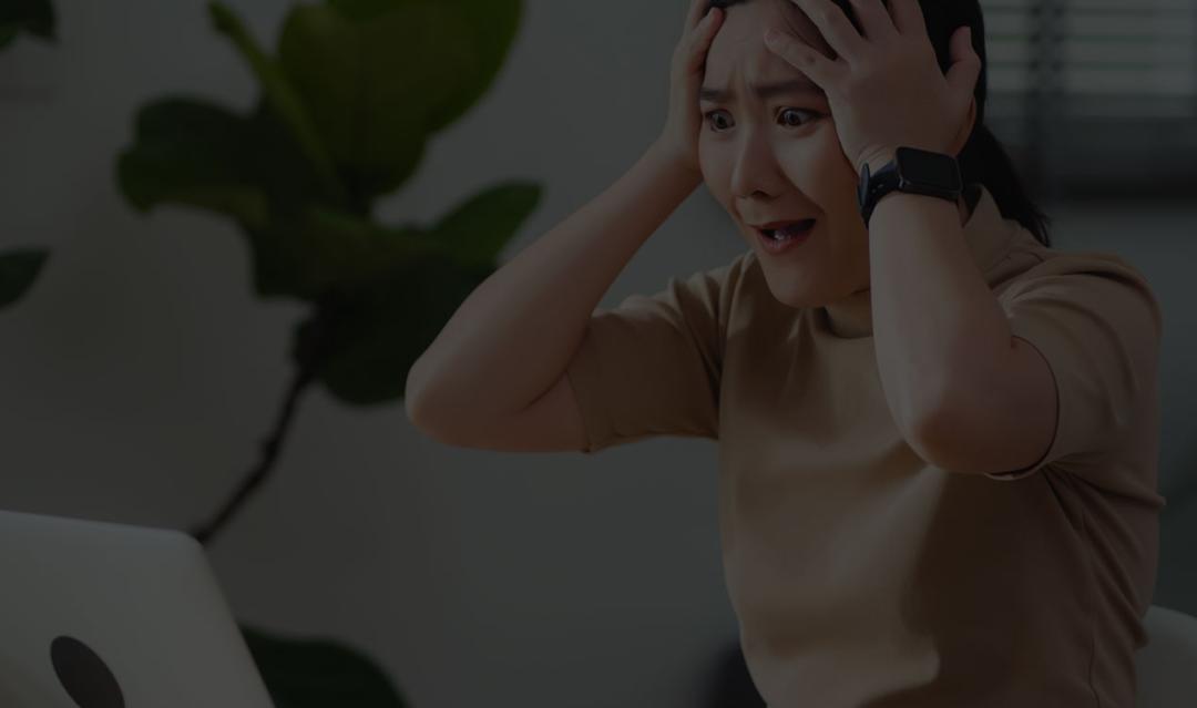 Woman sitting at home office, worried and concerned while looking at laptop