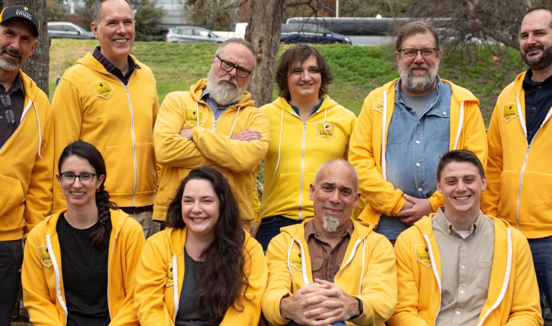 member of the Electric Citizen team gathered together outdoors, wearing matching gold hoodies