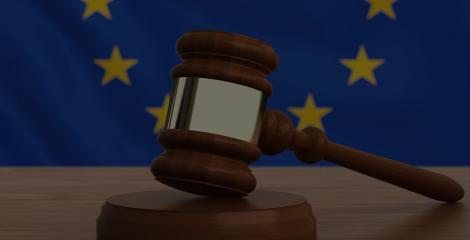 wooden gavel on a desk with the EU flag in the background