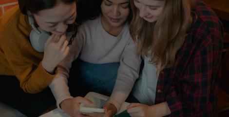 Group of friends gathered around a smartphone, using an app