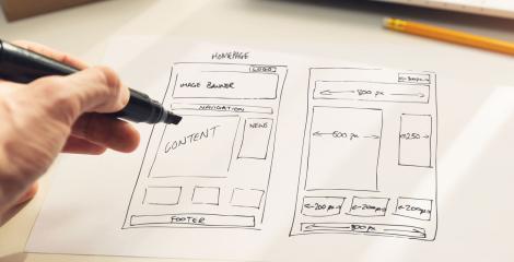 hand holding marker, sketching out a rough wireframe of page layout on paper