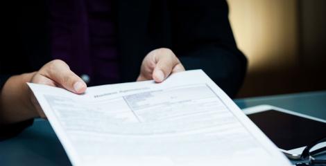 hands holding out a document, inside an office setting