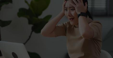 Woman sitting at home office, worried and concerned while looking at laptop