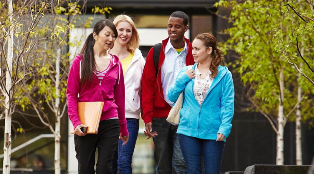 four college students walking together on campus, talking to each other