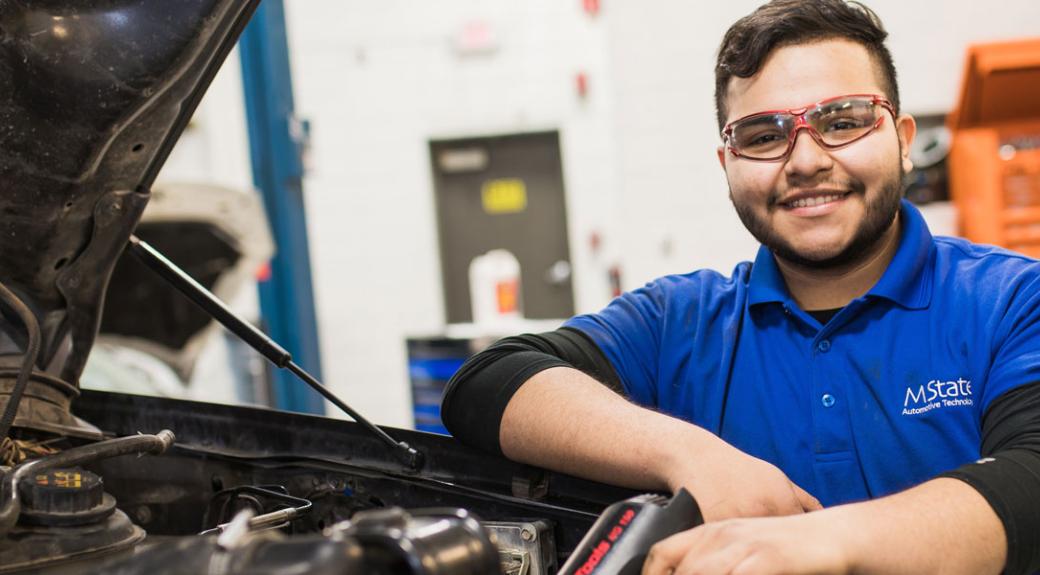 Automotive repair student in a garage with vehicle