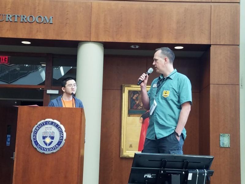 Dan and his co-host Les standing on stage with microphones, giving the 'welcome to the conference' presentation