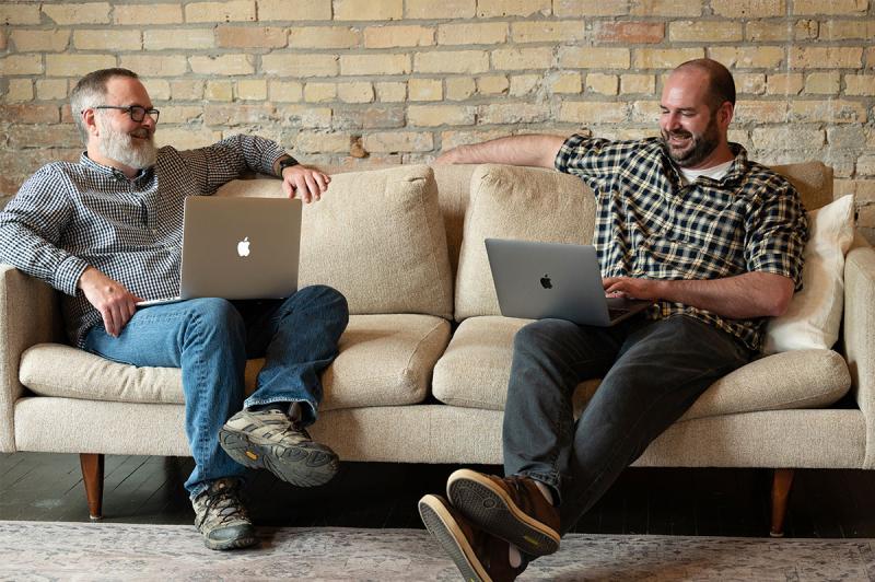 Briand and Adam on the couch together with laptops