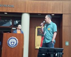 Dan and his co-host Les standing on stage with microphones, giving the 'welcome to the conference' presentation