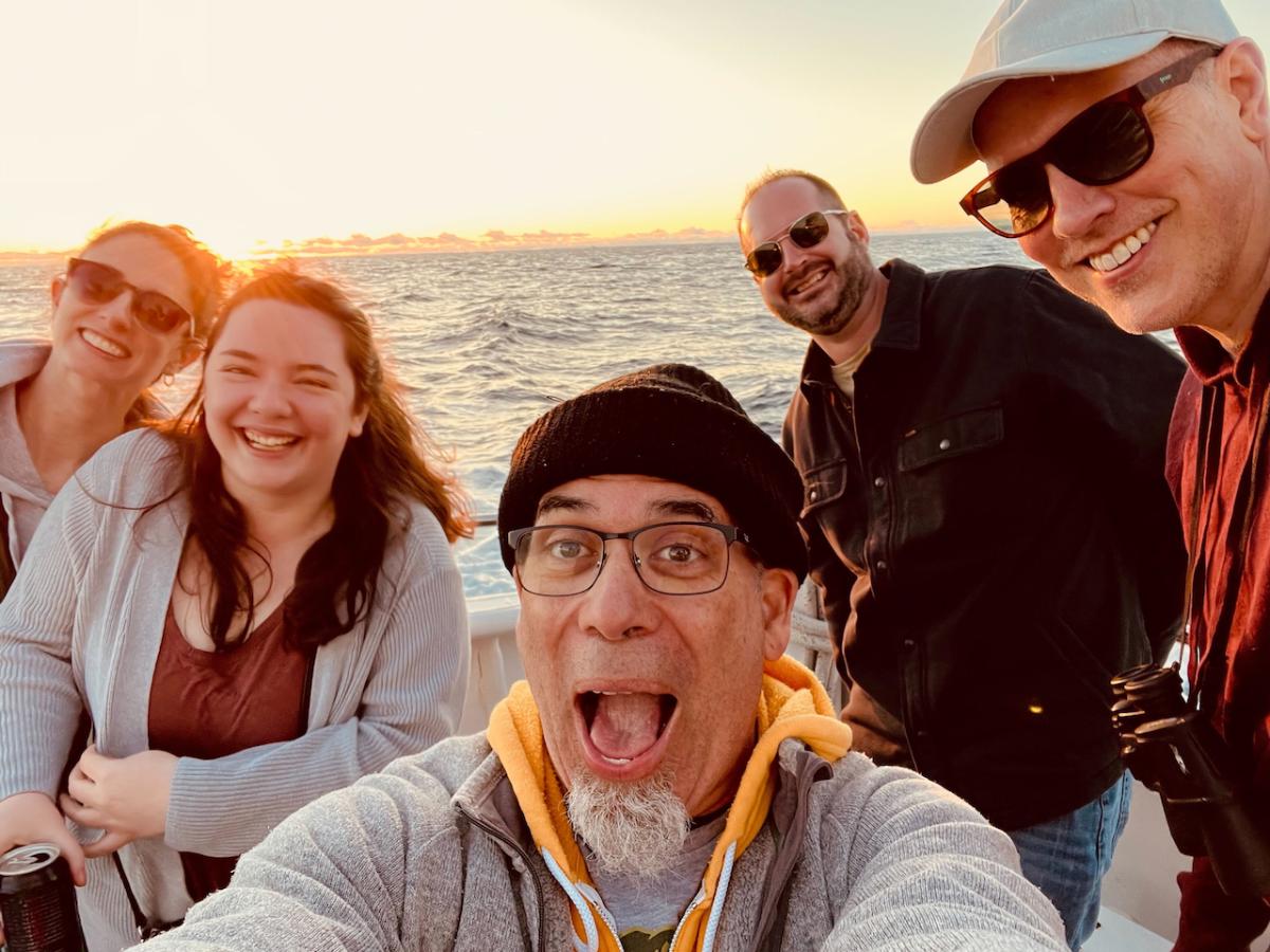several members of the EC team together on the boat at sunset