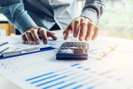 hands of person at work with paperwork and calculator spread out before them
