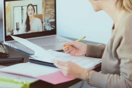 woman at desk having a conversation with another woman over her computer