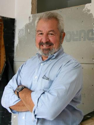 Bob Vila in front of drywall with arms crossed