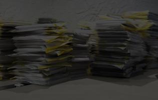 piles of papers stacked across the top of an office desk