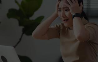 Woman sitting at home office, worried and concerned while looking at laptop