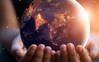 two hands holding a small, glowing globe against a dark background