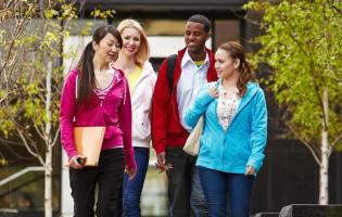 four college students walking together on campus, talking to each other