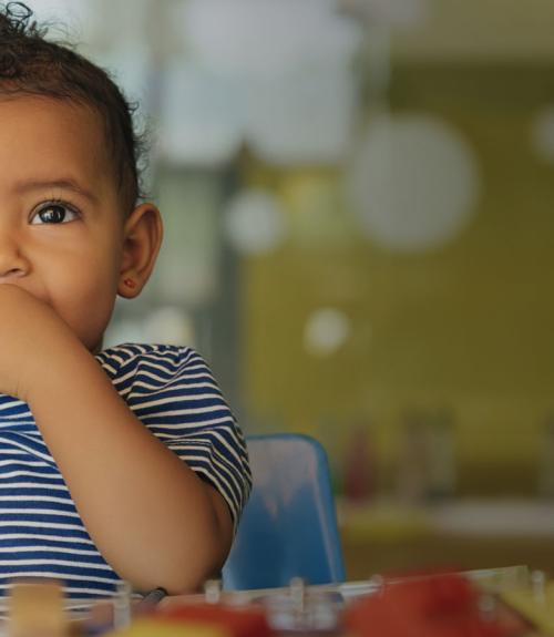 cute baby smiling and mouthing fingers in a daycare center