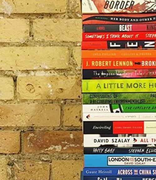 stack of published paperback books beside a brick wall