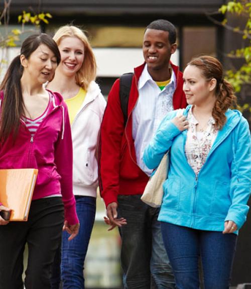 four college students walking together on campus, talking to each other