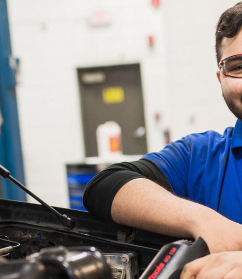 Automotive repair student in a garage with vehicle