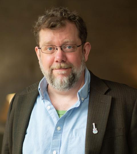 photo of tim broeker wearing a blue dress shirt and dark green jacket