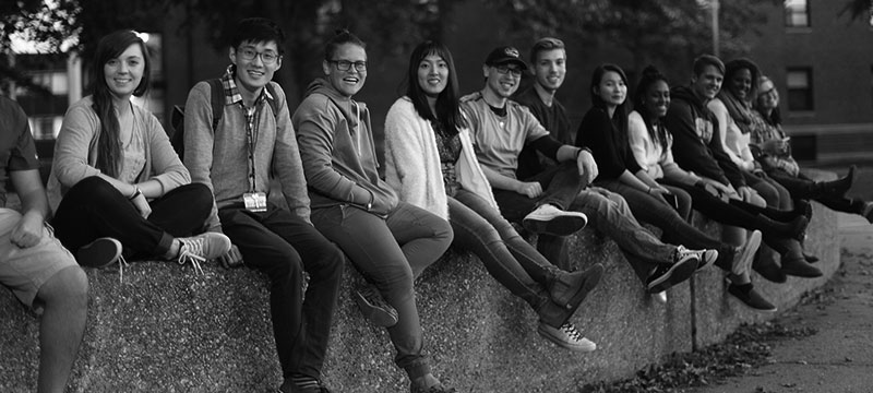 college students sitting together on a wall